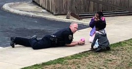 Cpl. C.B. Fleming playing dolls with Black kids
