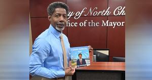 Mayor Reggie Burgess holding his children's book, A Leader Guided By God